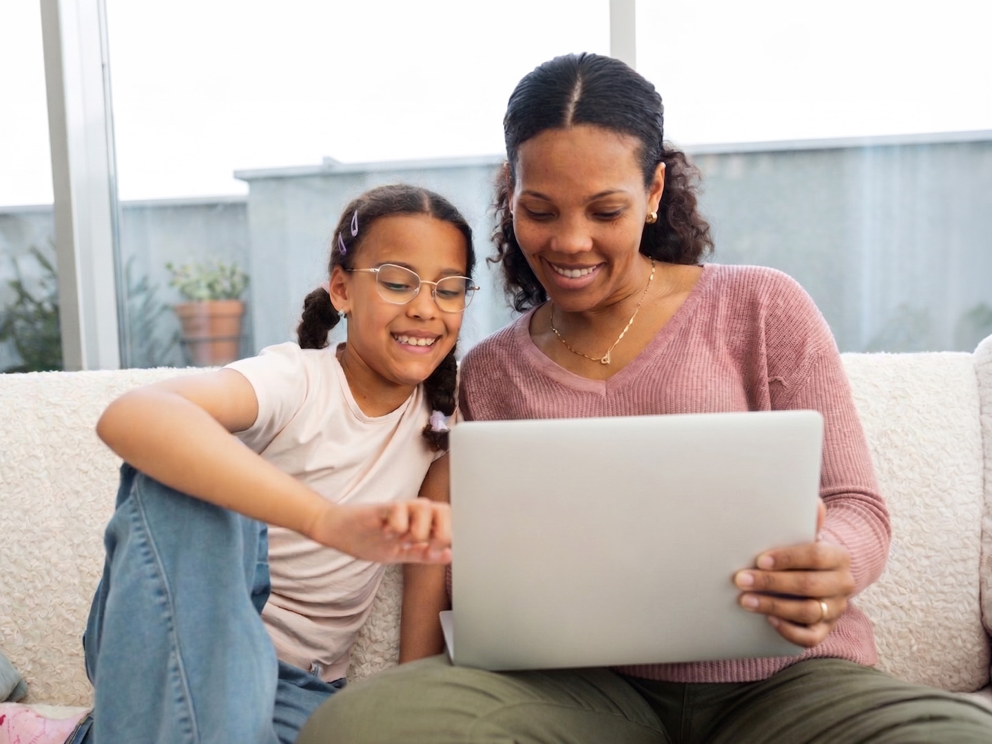 Mom and daughter looking at something together,  on their laptop.